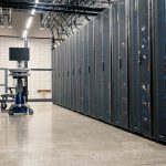 Gabinetes metálicos com servidores, equipamentos de rede e cabos em um datacenter moderno