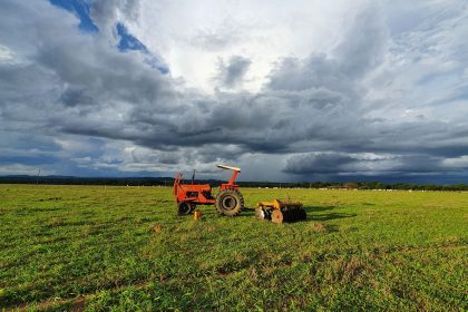 Trator parado em uma extensa plantação verde sob um céu carregado no campo brasileiro