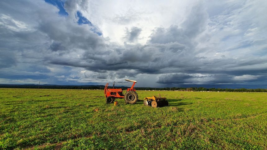 Trator parado em uma extensa plantação verde sob um céu carregado no campo brasileiro
