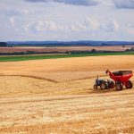 Trator colhe uma plantação em uma extensa área agrícola no Brasil.