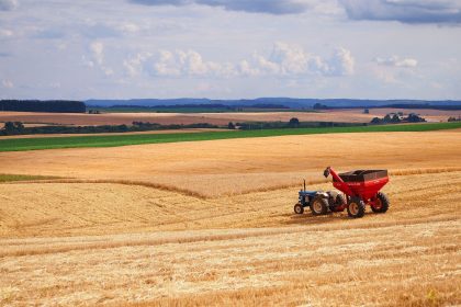 Trator colhe uma plantação em uma extensa área agrícola no Brasil.