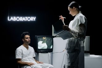 Dois pesquisadores analisam dados em um laboratório futurista enquanto conduzem um estudo com um participante.