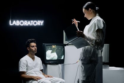 Dois pesquisadores analisam dados em um laboratório futurista enquanto conduzem um estudo com um participante.