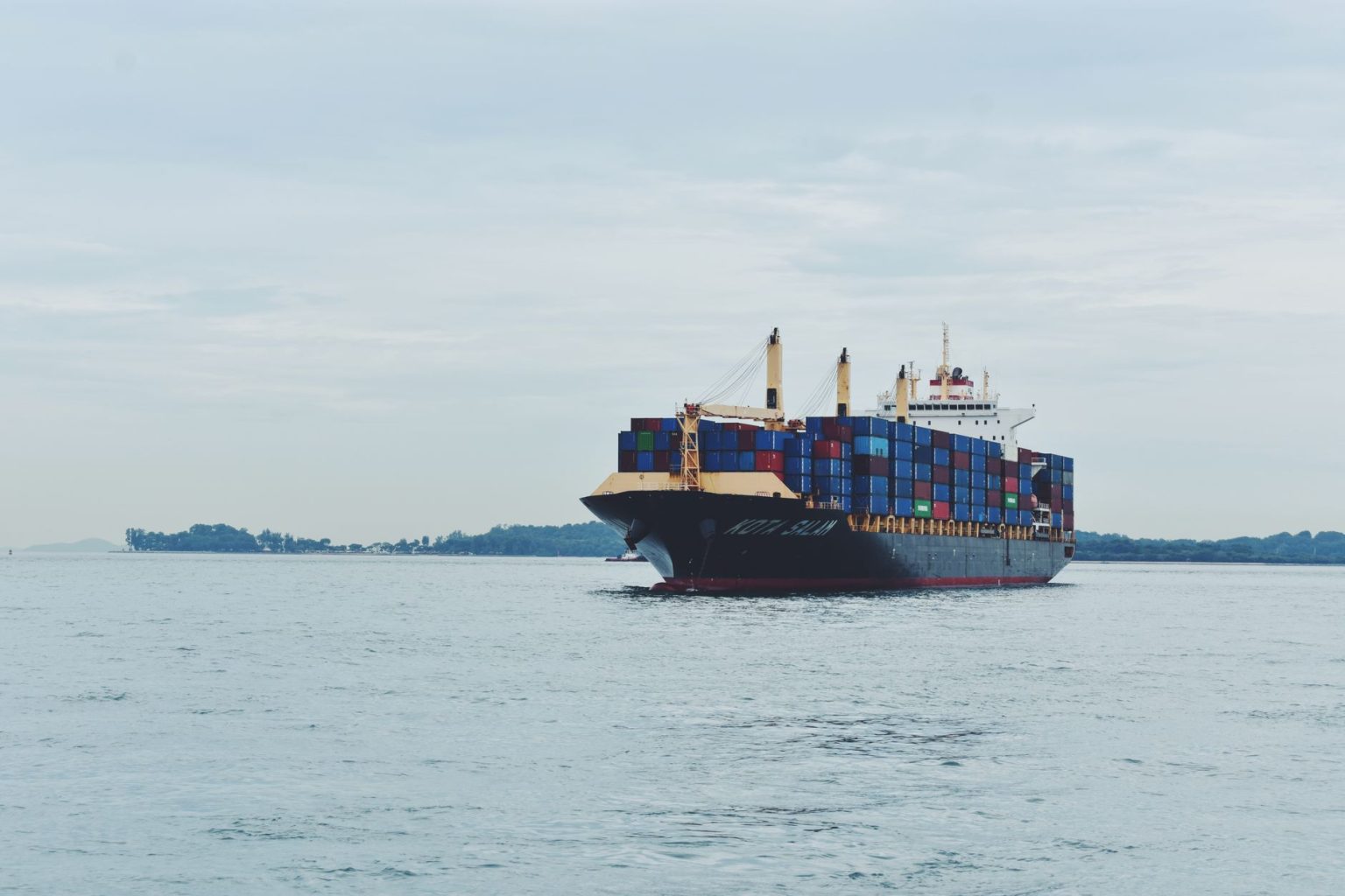 Navio cargueiro transportando contêineres pelo mar, em referência ao comércio internacional.