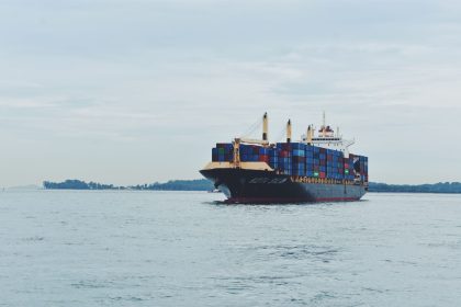 Navio cargueiro transportando contêineres pelo mar, em referência ao comércio internacional.