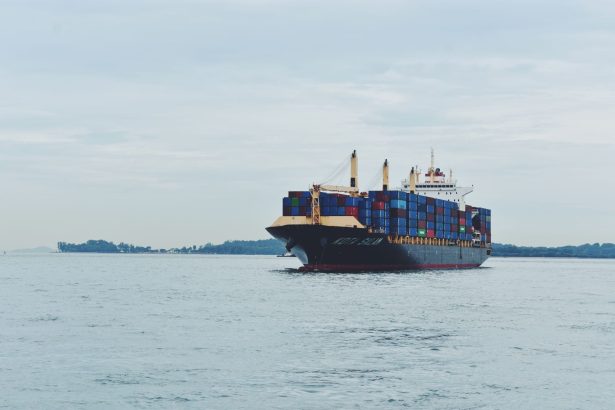 Navio cargueiro transportando contêineres pelo mar, em referência ao comércio internacional.