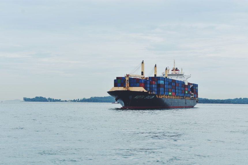 Navio cargueiro transportando contêineres pelo mar, em referência ao comércio internacional.